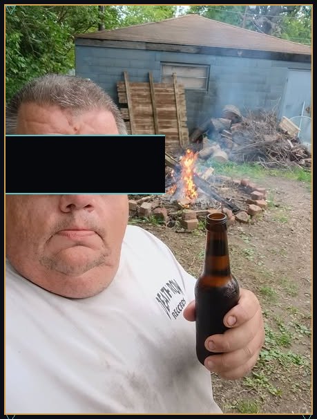 Jo outdoors by a backyard fire, with a solid bar across the eyes